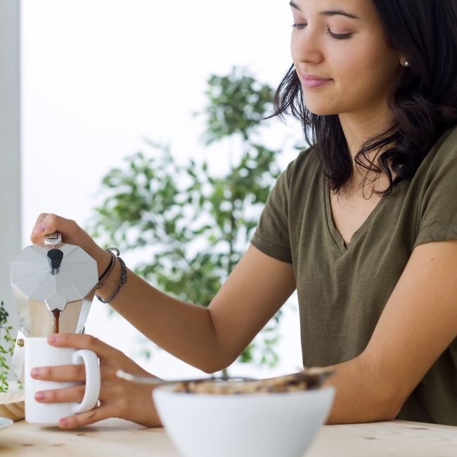 žena leje čerstvo pripravenú kávu do šálky