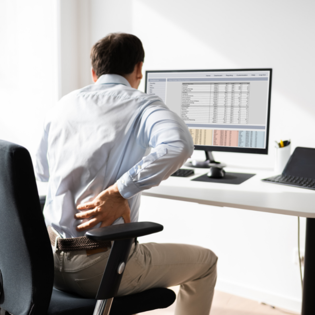 muž s bolesťou chrbta sedí za počítačom