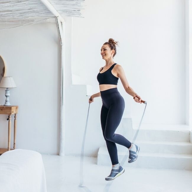 Žena ve sportovním skáče přes švihadlo a doplňuje pohyb krabičkovou stravou EasyDiet.