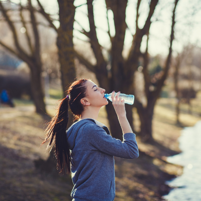 mladá žena pije vodu v prírode
