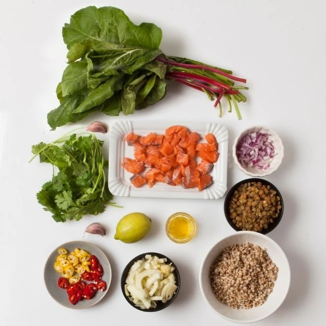 suroviny v miskách na prípravu zdravého šalátu zo šošovice, pohánky, mangoldu s lososom