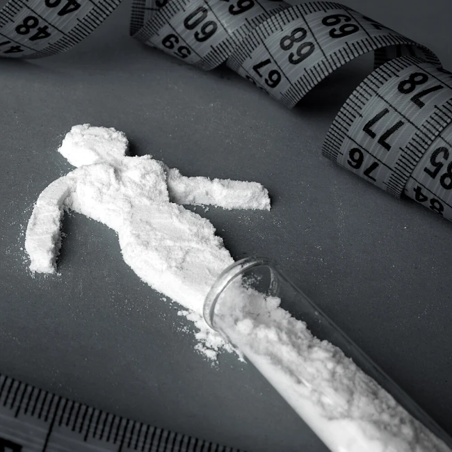 ženská postava vymodelovaná z prášku vysypaného zo skúmavky a krajčírsky meter