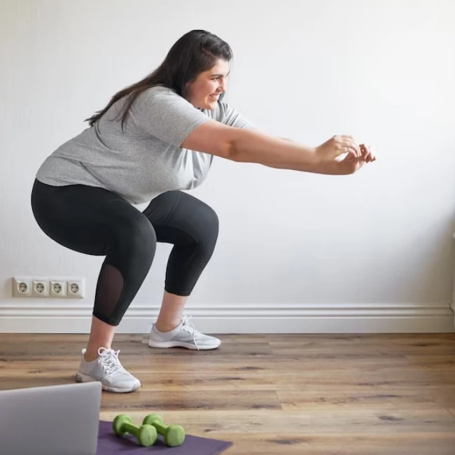 Junge übergewichtige Frau macht zu Hause Kniebeugen
