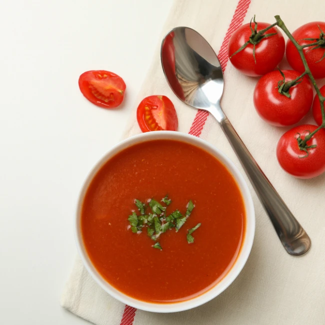 paradajková polievka v bielej miske posypaná nasekanou bazalkou