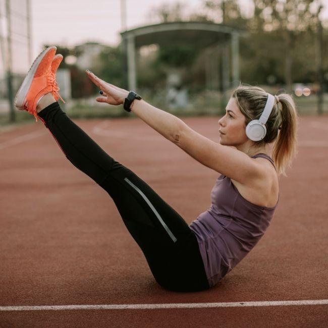 žena počúva hudbu a cvičí brušné svaly