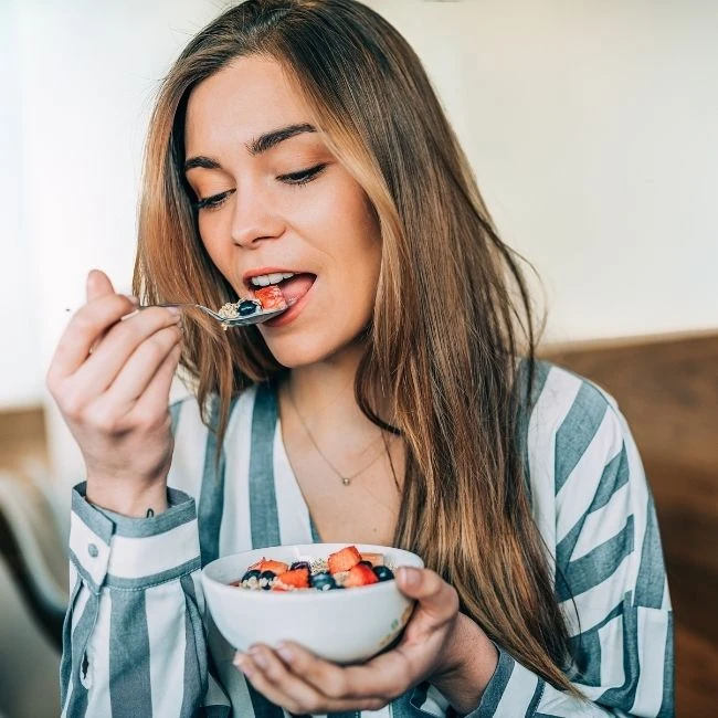 Žena si vychutnává cereální müsli s čerstvým ovocem, zdravá snídaně od EasyDiet.