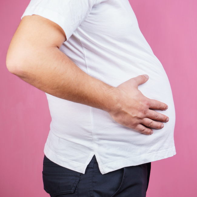 obézny muž v bielom tričku sa drží za brucho