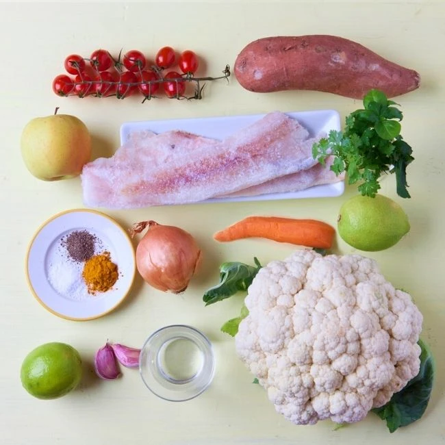 > Zutaten zum Kochen: Fischfilet, Blumenkohl, Süßkartoffel, Gemüse, Obst, Limetten und Gewürze.