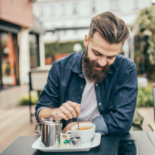 muž pije espresso na terase v kaviarni počas pracovnej pauzy
