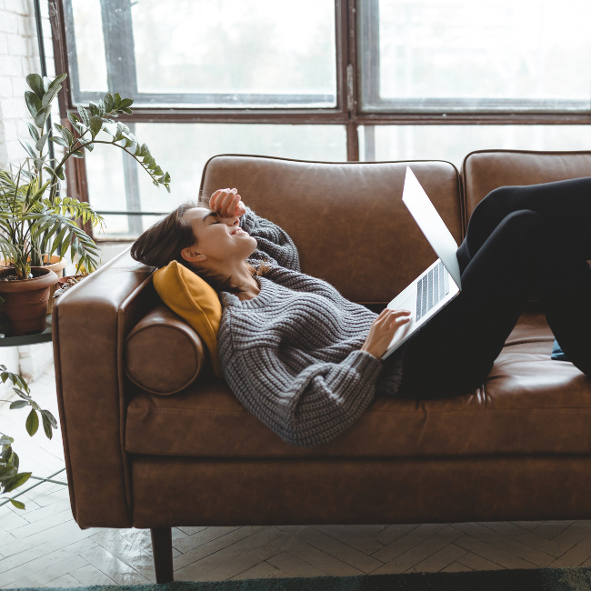 žena leží na gauči s notebookom na kolenách počas home office
